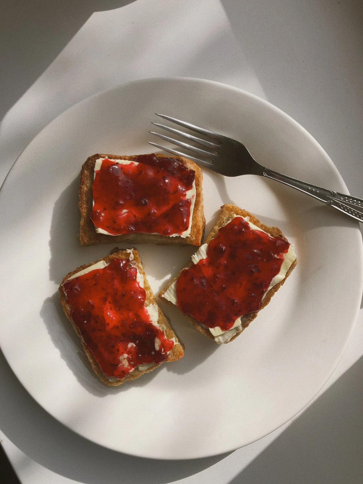 Jam-covered toast on a cream plate in warm natural light